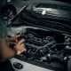 Mechanic inspecting a car engine for maintenance work in a garage.