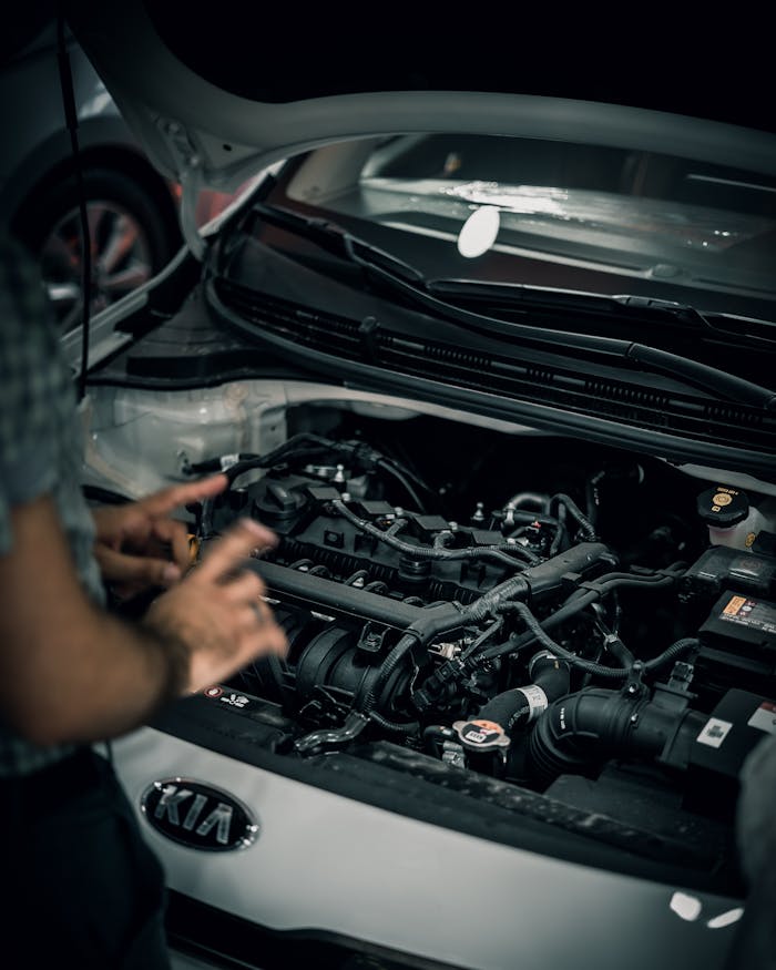 Mechanic inspecting a car engine for maintenance work in a garage.